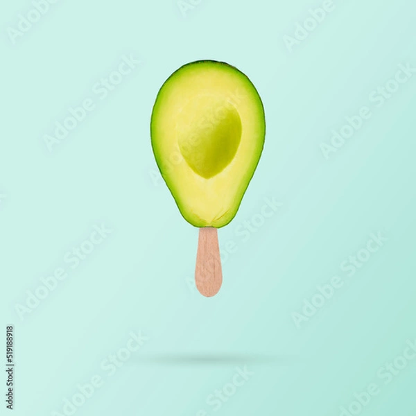 Obraz Fresh green avocado with ice cream stick on pastel blue background. Diet healthy concept. Creative summer concept..