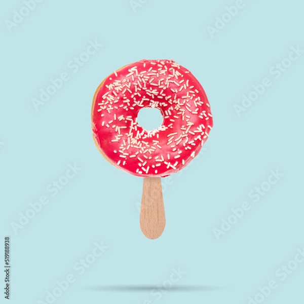 Obraz Pink donut Donut with sprinkles and ice cream stick on pastel blue background. Sweets concept. Creative summer concept..