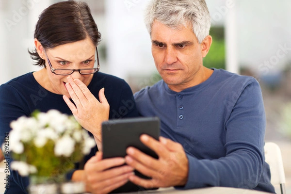 Fototapeta middle aged couple reading shocking news
