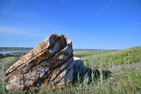 Obraz blue skies and a large splitting lichen covered sandstone rock on a  green hillside of a valley