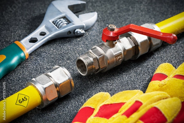 Obraz yellow gas pipe, wrench and protective gloves on dark tile surface. concept of repair gas pipeline in the house.