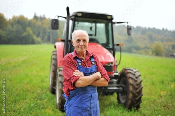 Fototapeta Dumny rolnik stojący przed swoim czerwonym traktorem