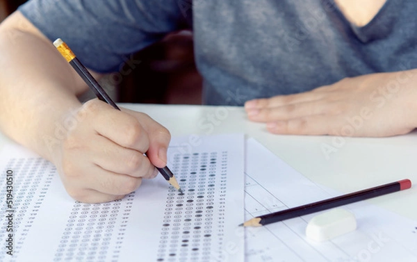 Fototapeta Students hand holding pencil writing selected choice on answer sheets and Mathematics question sheets. students testing doing examination. school exam