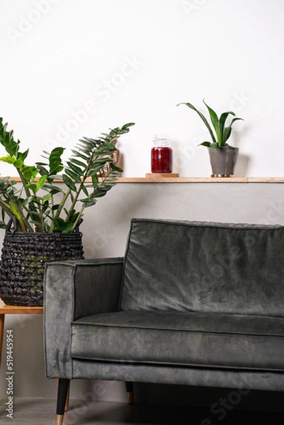 Fototapeta Decoration in interior: blank crimson pillar candle in glass jar without label on a wooden table in front of couch and indoor plant - a living room set-up