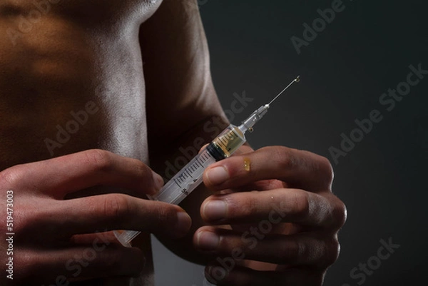 Fototapeta Muscular man with a syringe in his hand. User of anabolic steroids for strength training