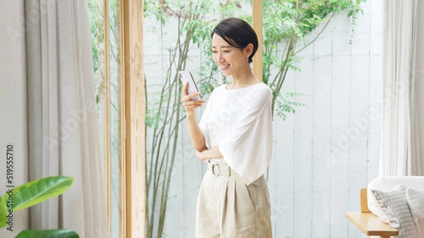 Fototapeta 笑顔でスマホを見るミドル女性