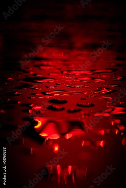 Fototapeta Beautiful macro photo of water drop reflection, lying on surface, front view. Close up of red liquid with side lighting from displays.
