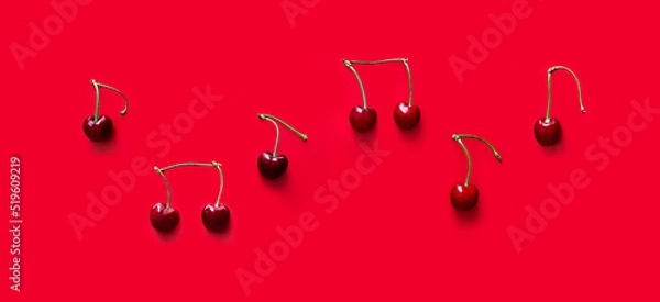 Fototapeta on red background notes from berries sweet cherry red color place inscription music notation camp copy space banner