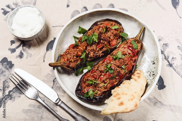 Fototapeta Imam bayildi. Traditional delicious Turkish food: halves of baked eggplant stuffed with vegetables on a plate. Selective focus