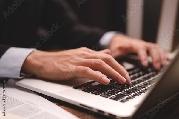 Fototapeta closeup business hand working to typing computer laptop keyboard in modern office or home workplace desk table, businessman using notebook for online technology communication job by using cyberspace