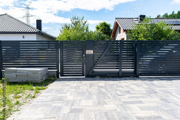 Obraz A modern panel fence in anthracite color, a visible sliding gate to the garage and a wicket with a letterbox.