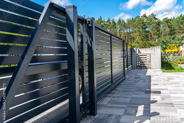 Obraz Modern panel fencing in anthracite color, visible sliding gate to the garage as well as a handle and a lock.