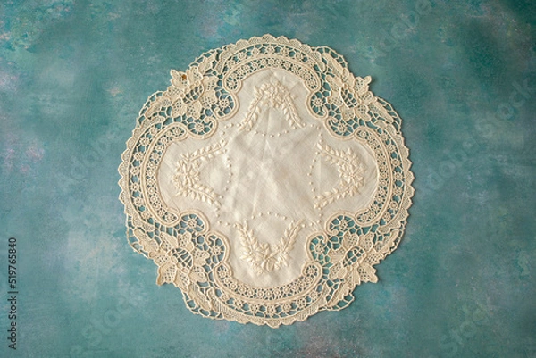 Fototapeta A single lacy doyley shot from above on a green textured background, space for text