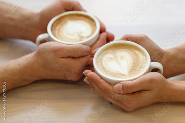 Fototapeta Couple drinking coffee in a cafe man and woman with a cup of hot latte. Selective focus.