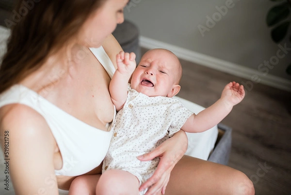 Fototapeta Newborn crying boy. the child is tired and hungry in the arms of the mother. children are crying. infant cry.