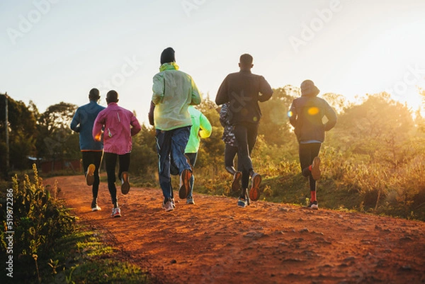 Fototapeta Morning running training. in Kenya. Marathon runners on red soil train in the light of the rising sun. Motivation to move. Endurance running, athletics and sports