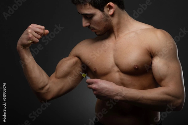 Fototapeta Muscular man with a syringe in his hand. User of anabolic steroids for strength training.