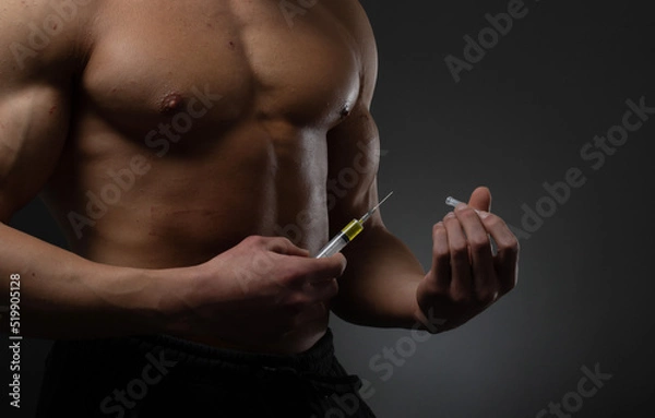 Fototapeta Muscular man with a syringe in his hand. User of anabolic steroids for strength training.