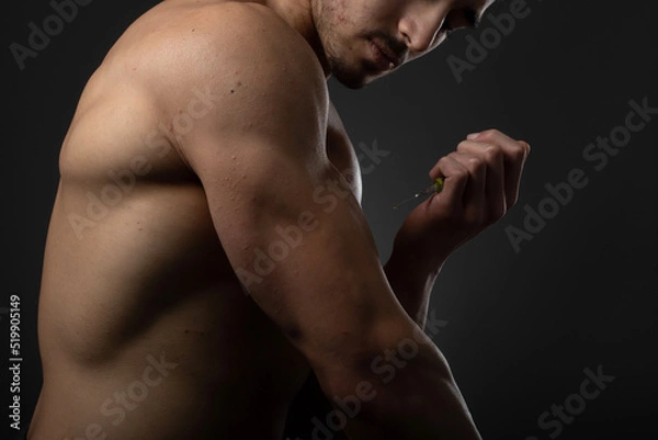 Obraz Muscular man with a syringe in his hand. User of anabolic steroids for strength training.