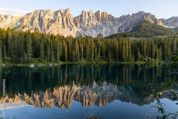 Fototapeta Splendid view of Lake Carezza in South Tyrol. The mountains and the forest are perfectly reflected on the lake, a suggestive image. A dream place for a relaxing holiday in nature.
