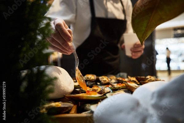Obraz waiter adding sauce on mussels during catering