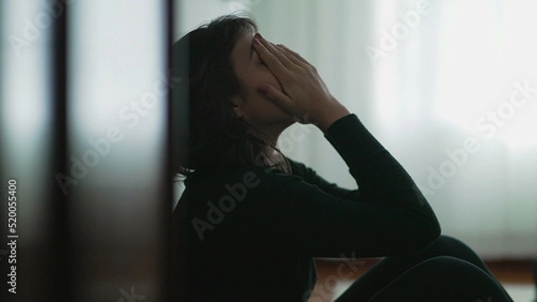 Fototapeta Depressed woman sitting on floor covering face with hands in despair