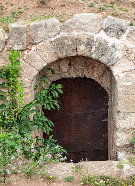 Fototapeta This entryway can be found in Belogradchik Rocks area. It is somewhat hidden and appears to go underground. The wood door is closed.