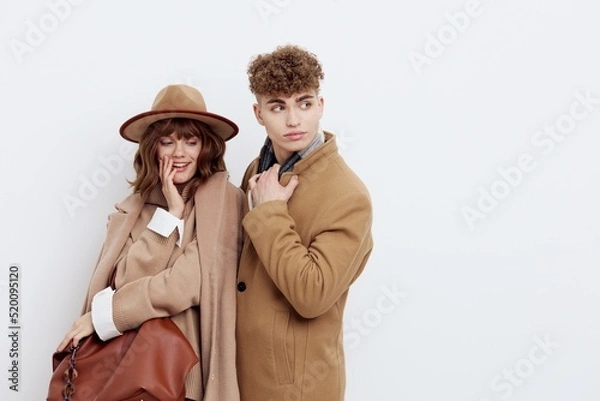Fototapeta a happy couple a man and a woman stand in stylish autumn clothes on a white background close to each other and smile happily