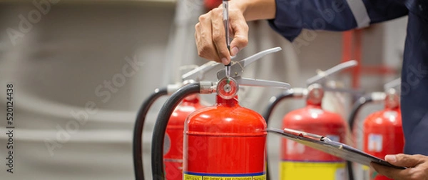 Fototapeta Engineer are checking and inspection a fire extinguishers tank in the fire control room for safety training and fire prevention.