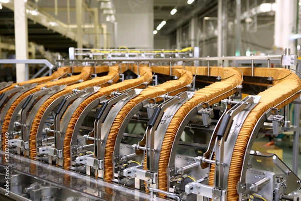 Fototapeta A lot of cookies on the production line. The flow of sweets before packaging. Packing crackers on the machine. Innovative production.