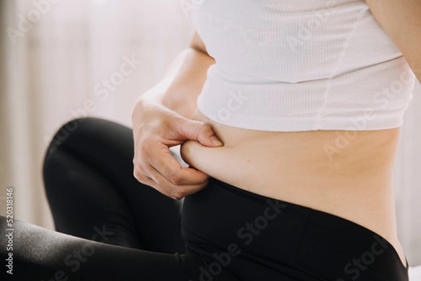 Fototapeta Beautiful fat woman with tape measure She uses her hand to squeeze the excess fat that is isolated on a white background. She wants to lose weight, the concept of surgery and break down fat under the