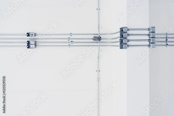 Obraz electric steel box and pipe on white concrete background. Electricity cable pipe line with box, the brilliant invention of modern electrical technology
