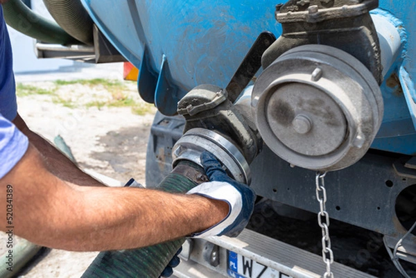 Obraz The man connects a 4 inch PVC suction hose to the flange fitting on the trucks tank.