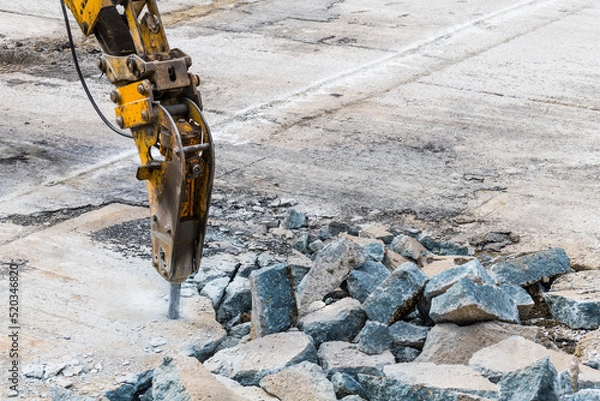 Fototapeta Excavator mounted hydraulic jackhammer at breaking concrete area. Closeup of working demolition hammer with point bit. Heavy equipment detail on construction site. Carpark renewing. Civil engineering.