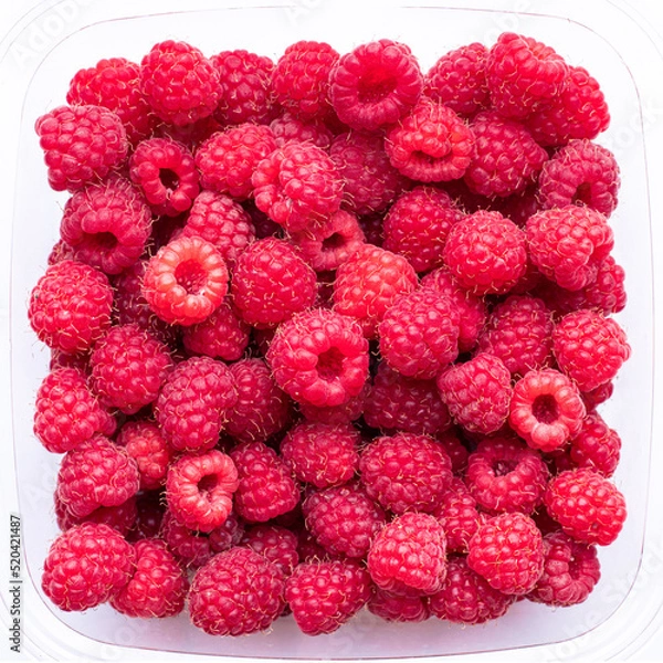 Fototapeta Red raspberries in a transparent plastic container, top view