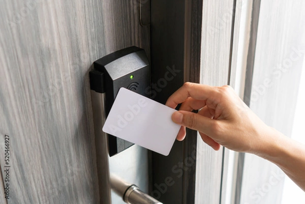 Fototapeta Woman hand using electronic smart key card to unlock door in hotel or house. Digital lock, door access control, contactless concept. Closeup, copy space