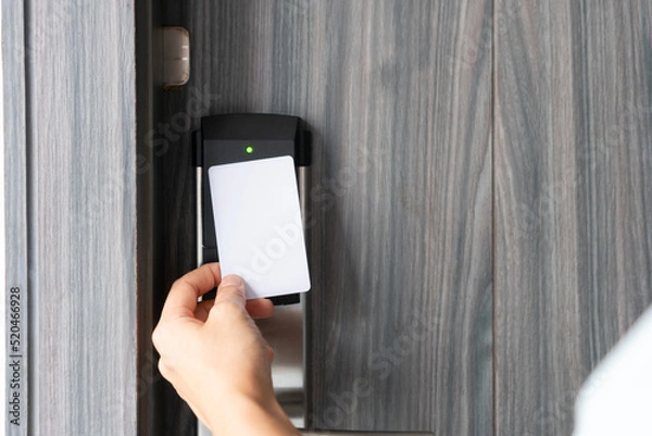 Fototapeta Woman hand using electronic smart key card to unlock door in hotel or house. Digital lock, door access control, contactless concept. Closeup, copy space