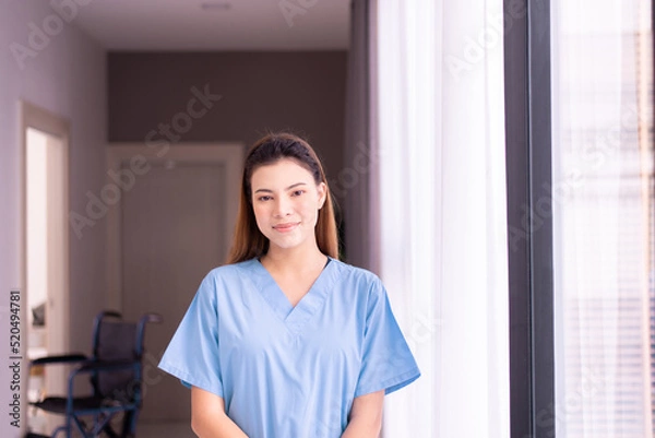Obraz Portrait of beautiful nurse standing and smiling in a nursing home