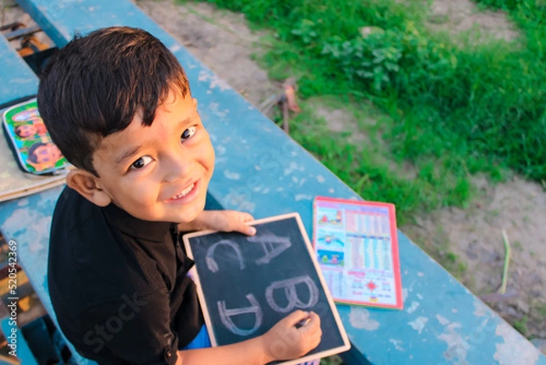 Obraz Indian 5 year child writing A B C D alphabet on chalkboard,abcd alphabet