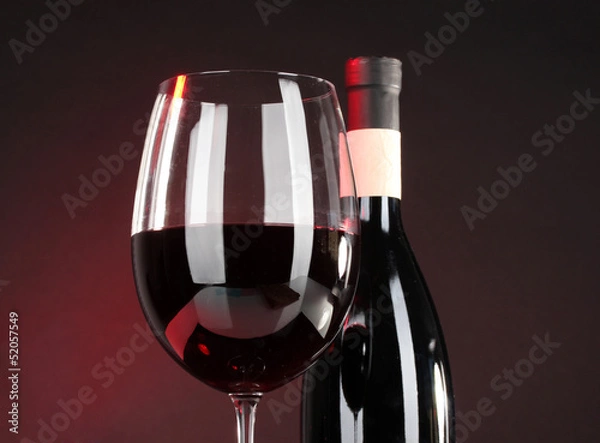 Obraz Wine in glass and wine bottle close-up on dark background
