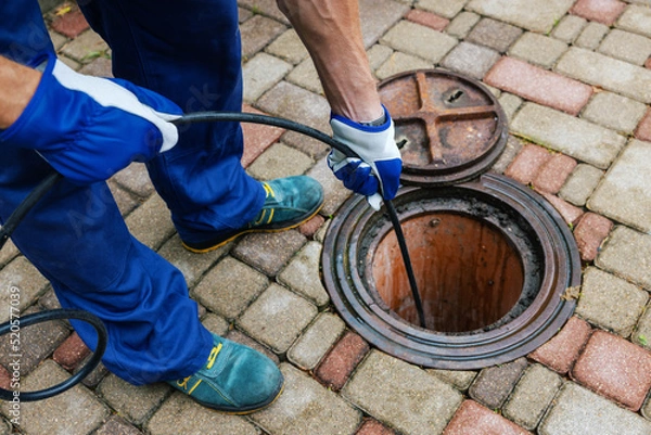 Fototapeta sewer cleaning service - worker clean a clogged drainage with hydro jetting