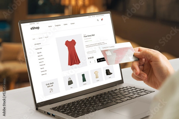 Fototapeta Shopping online with credit card concept. Modern e-commerce web page with woman clothes on laptop display