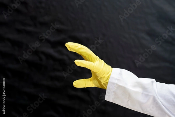 Obraz A doctor in a medical gown and protective gloves threatens with an open palm. The face is not visible.