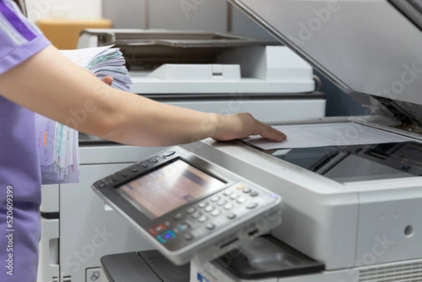 Fototapeta Woman standing and pressing button button on panel of printer, printer scanner laser office copy machine supplies in the office