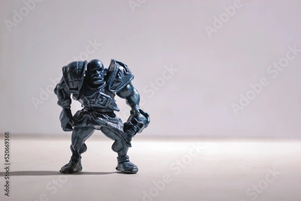 Obraz A figurine of an aggressive and vicious bald warrior in armor with a skull stands on a gray background