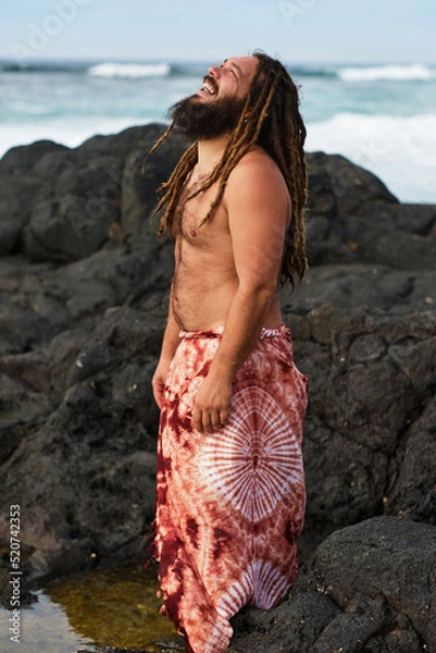 Fototapeta vertical photo, bearded rasta boy smiling, happy and contented by the sea