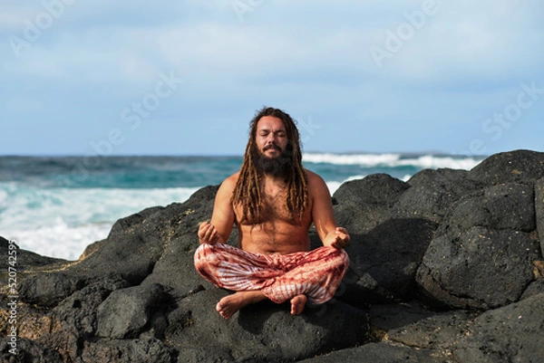 Obraz rasta boy meditating in lotus position, by the sea