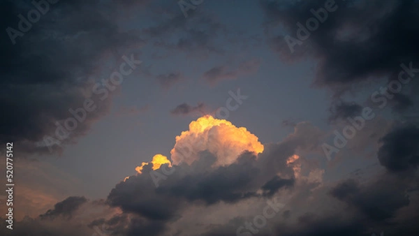 Fototapeta An orange cloud in the cloudy evening sky