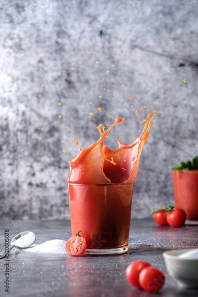 Obraz tomato juice, pour tomato juice into a glass, splashes of tomato juice, on a gray background, space for text, cherry tomatoes and salt 