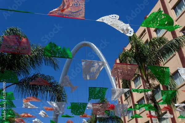 Fototapeta low view of tijuana mexico street with colorful party decorations with view to the arch